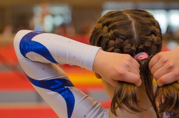 Young gymnast girl fixing hair before appearance