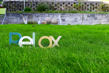 Lettering "Relax" made of wood in green meadow in a garden