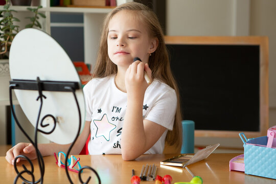 A beautiful girl with Down syndrome combs in front of a mirror