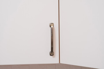 The metal handle on the kitchen cabinet door.