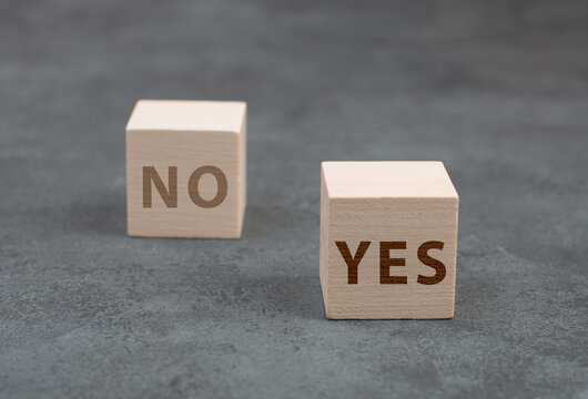 Two wooden cubes, onewith the word yes, the second one with no, dark background
