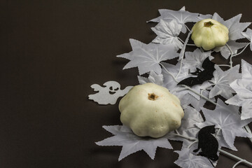 Halloween concept. Ghostly white maple leaves on a branch, pumpkins