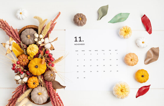 Flat lay with calendar for november with autumn table decoration. Floral interior decor for fall holidays with handmade pumpkins. Flatlay, top view