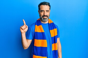 Middle age man with beard and grey hair football hooligan cheering game smiling with an idea or question pointing finger up with happy face, number one