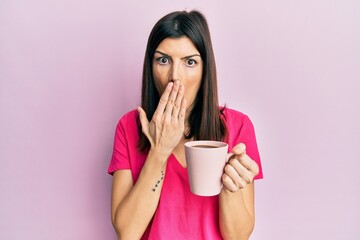 Young hispanic woman drinking a cup of coffee with angry face, negative sign showing dislike with thumbs down, rejection concept