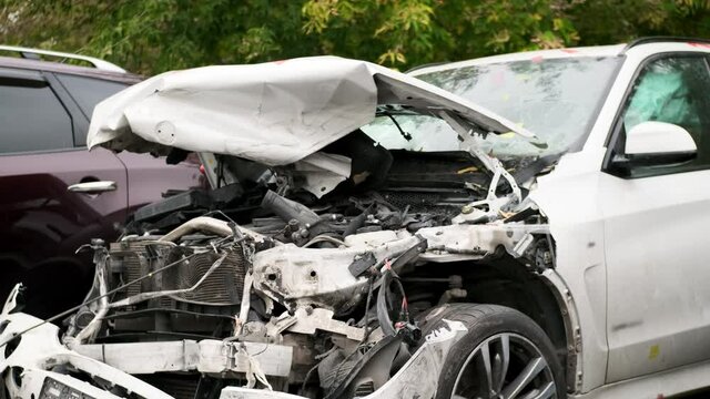 close up of wrecked car with broken windshield, Car crash accident damaged windshield triplex is broken on white car, nature of dent resembles an accident involving pedestrian.