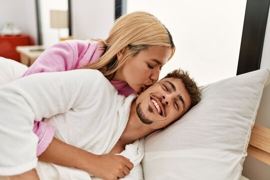 Young caucasian couple kissing and hugging lying on the bed at home.