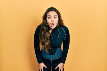 Young hispanic girl wearing diver neoprene uniform afraid and shocked with surprise and amazed expression, fear and excited face.