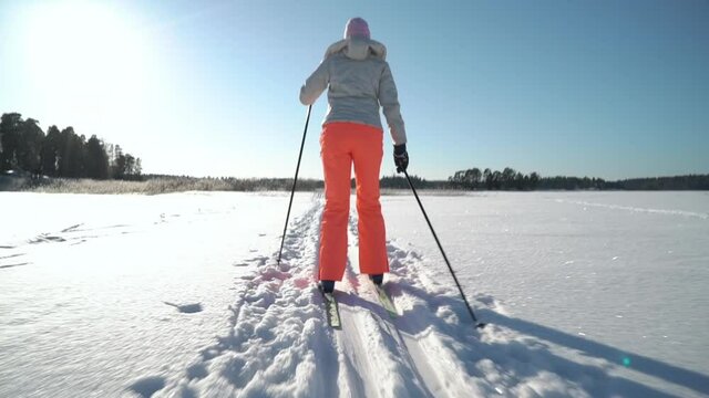 A woman going cross-country skiing on a frozen bay in Finland on a frosty sunny day. Steadicam Tracking Shot.
