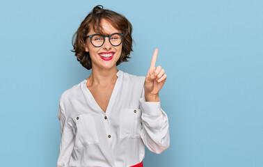 Young hispanic woman wearing business style and glasses showing and pointing up with finger number one while smiling confident and happy.