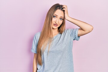 Young blonde girl wearing casual t shirt confuse and wonder about question. uncertain with doubt, thinking with hand on head. pensive concept.