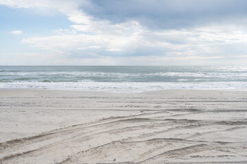 Dark storm clouds over a calm ocean at high tide with winds sweeping in land and carrying rain...