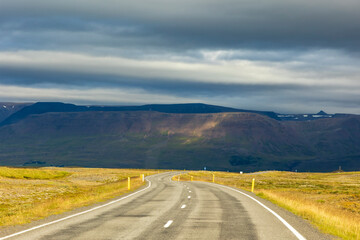 summer road trip on an open high way in Route 1 in Iceland with dramatic mountain landscape on the background.