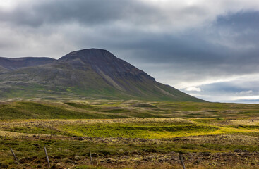 summer road trip on an open high way in Route 1 in Iceland with dramatic mountain landscape on the background.