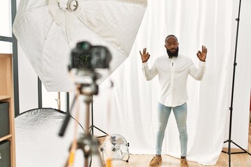 African american man posing as model at photography studio relax and smiling with eyes closed doing meditation gesture with fingers. yoga concept.