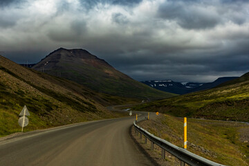 summer road trip on an open high way in Route 1 in Iceland with dramatic mountain landscape on the background.