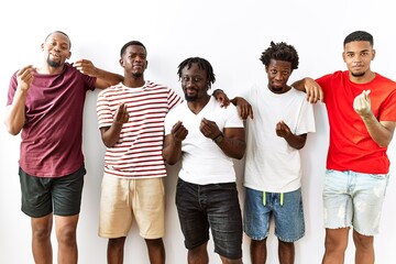 Young african group of friends standing together over isolated background doing money gesture with hands, asking for salary payment, millionaire business