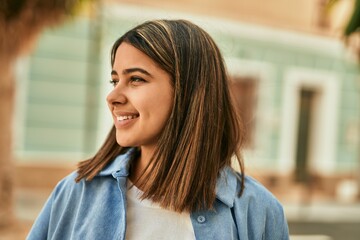 Young latin girl smiling happy standing at the city.