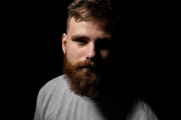 Close-up portrait of a handsome a brunette brutal bearded man in a grey t-shirt. Stylish and handsome man with a beard.