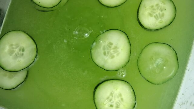 Refreshing cucumber drink in glass container above white surface