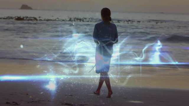 Animation of light trails over caucasian woman walking on beach