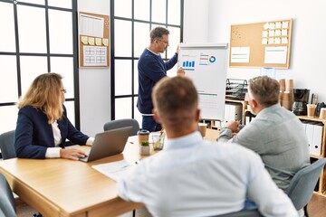 Group of middle age business workers listening boss conference during meeting at the office.
