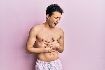 Young handsome man wearing swimwear shirtless with hand on stomach because nausea, painful disease feeling unwell. ache concept.