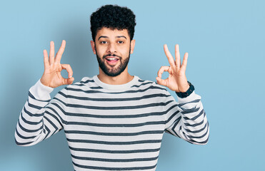 Young arab man with beard wearing casual striped sweater looking surprised and shocked doing ok approval symbol with fingers. crazy expression