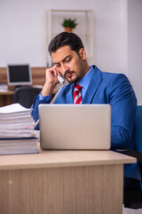 Young male employee unhappy with excessive work at workplace