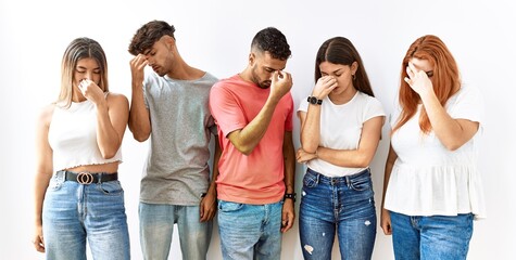 Group of young friends standing together over isolated background tired rubbing nose and eyes feeling fatigue and headache. stress and frustration concept.