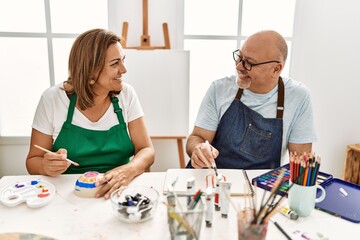 Middle age hispanic painter couple smiling happy painting at art studio.