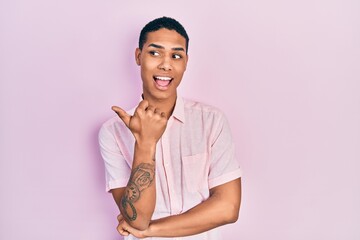 Young african american guy wearing casual clothes smiling with happy face looking and pointing to...