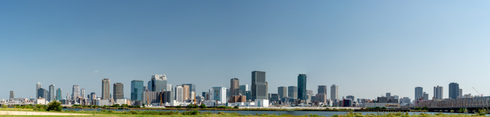 Panoramic view of office buildings of central Osaka city from Yodogawa river bank - obrazy, fototapety, plakaty