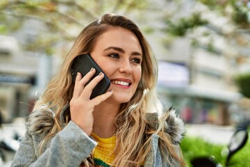 Young blonde woman speaking on the phone at the park