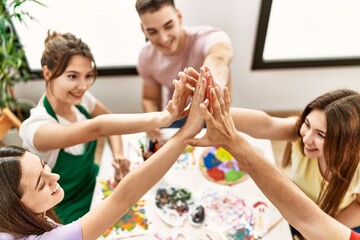 Group of people sitting on the table with united hands at art studio.