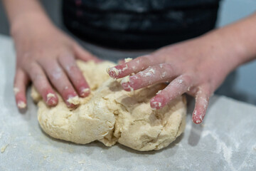 child kneading dough on table