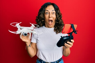 Middle age hispanic woman using drone celebrating crazy and amazed for success with open eyes screaming excited.