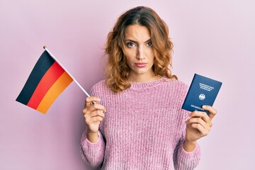 Young caucasian woman holding germany flag and passport skeptic and nervous, frowning upset because of problem. negative person.