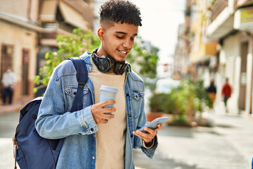 Hispanic young man using smartphone drinking a coffee at the street