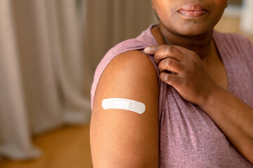 African american senior woman showing plaster after vaccination - obrazy, fototapety, plakaty