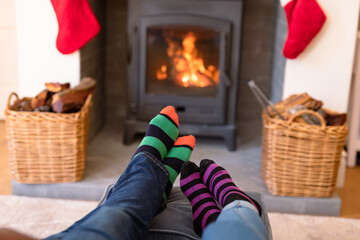 Feet of couple wearing christmas socks and resting on sofa close to fireplace at christmas time
