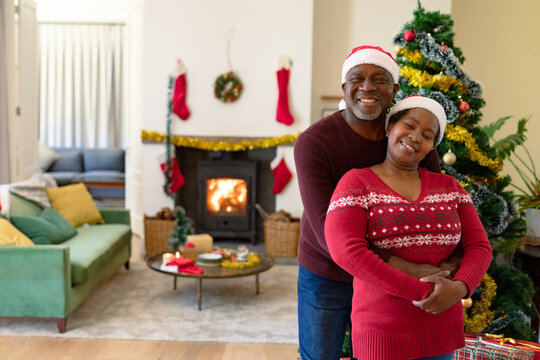 Happy african american senior couple in santa hats taking photo at christmas time