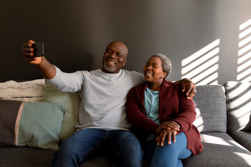 Naklejka premium Happy african american senior couple taking selfie at home