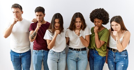 Group of young friends standing together over isolated background feeling unwell and coughing as symptom for cold or bronchitis. health care concept.