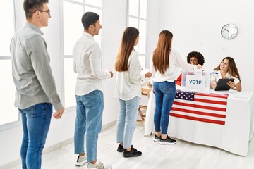 Fototapeta premium Group of young american voter people putting vote in ballot standing at electoral center.