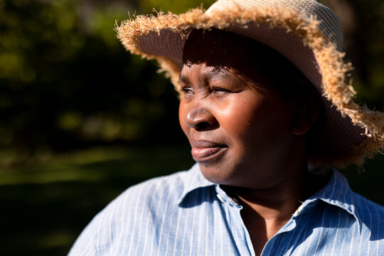 Portrait of african american senior woman wearing hat, looking into distance outdoors