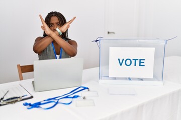 Young african american woman working at political election sitting by ballot rejection expression...