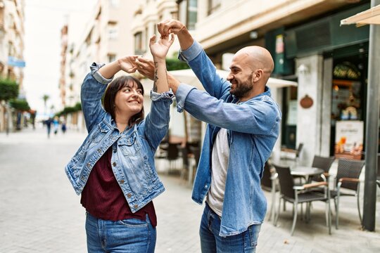 Young hispanic couple smiling happy dancing at the city.