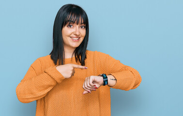 Young hispanic woman wearing casual clothes in hurry pointing to watch time, impatience, upset and...