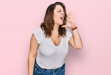 Young plus size woman wearing casual white t shirt shouting and screaming loud to side with hand on mouth. communication concept.